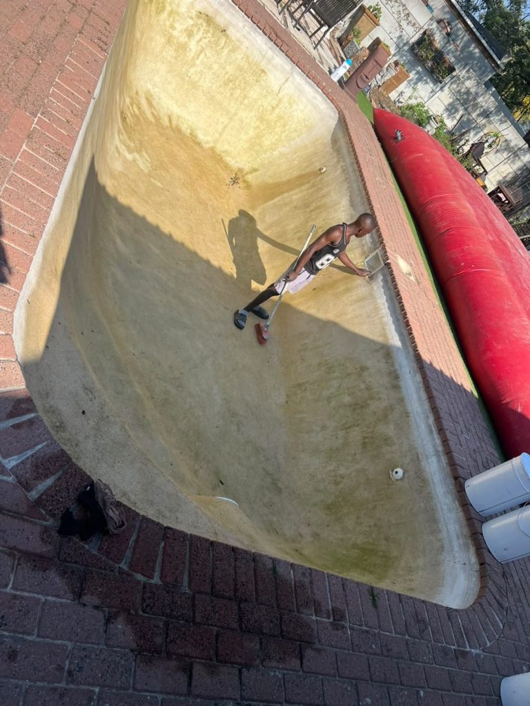 Drained gunite pool shell in Durbanville showing stained cracked surface