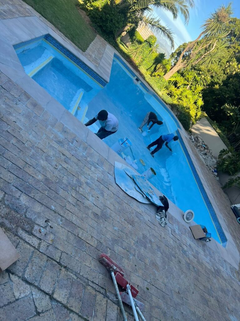 Pool relining Bellville: crew cleaning a finished fibreglass pool with new copings
